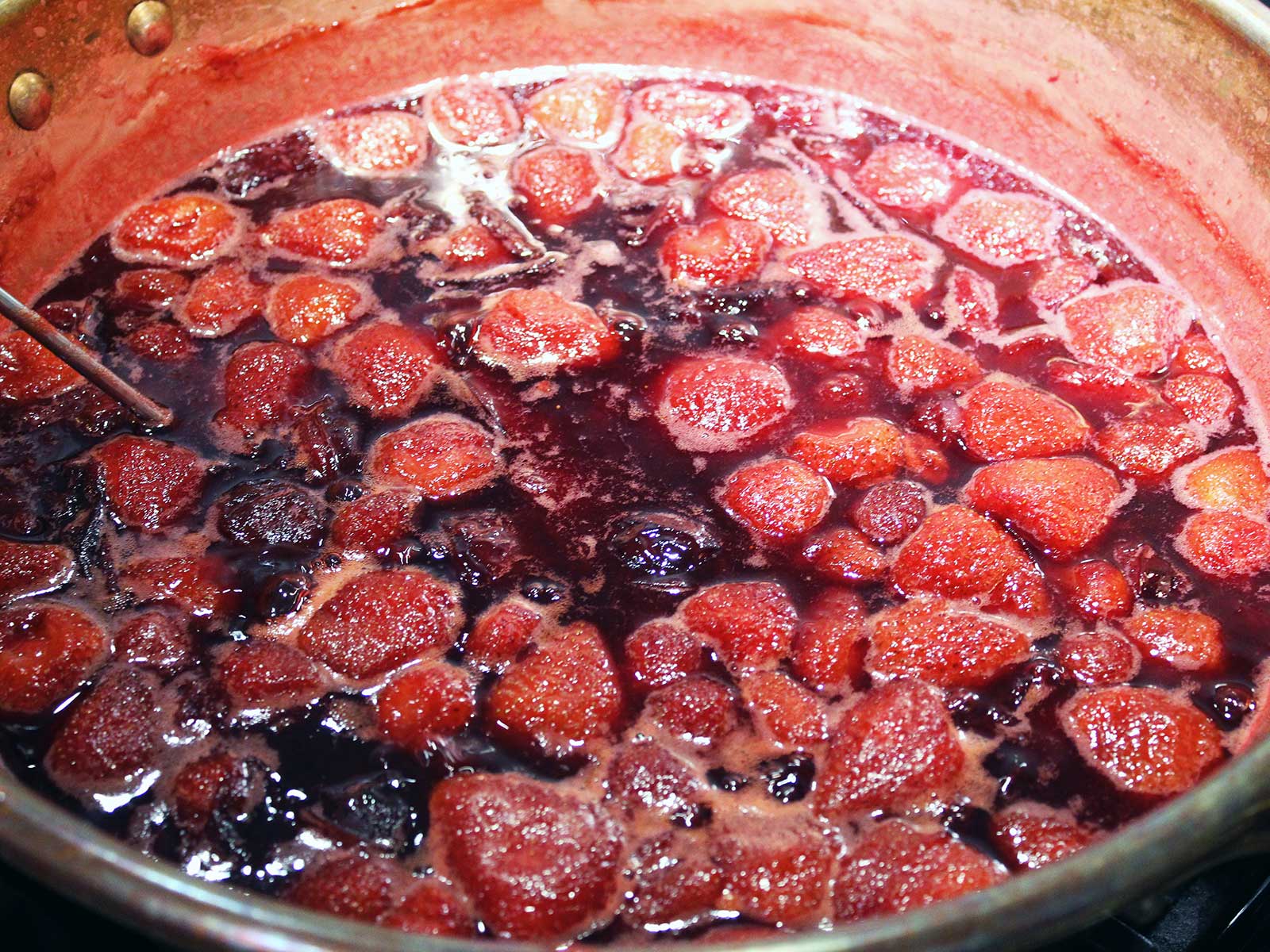 Strawberries and Pluots cooking in copper pan