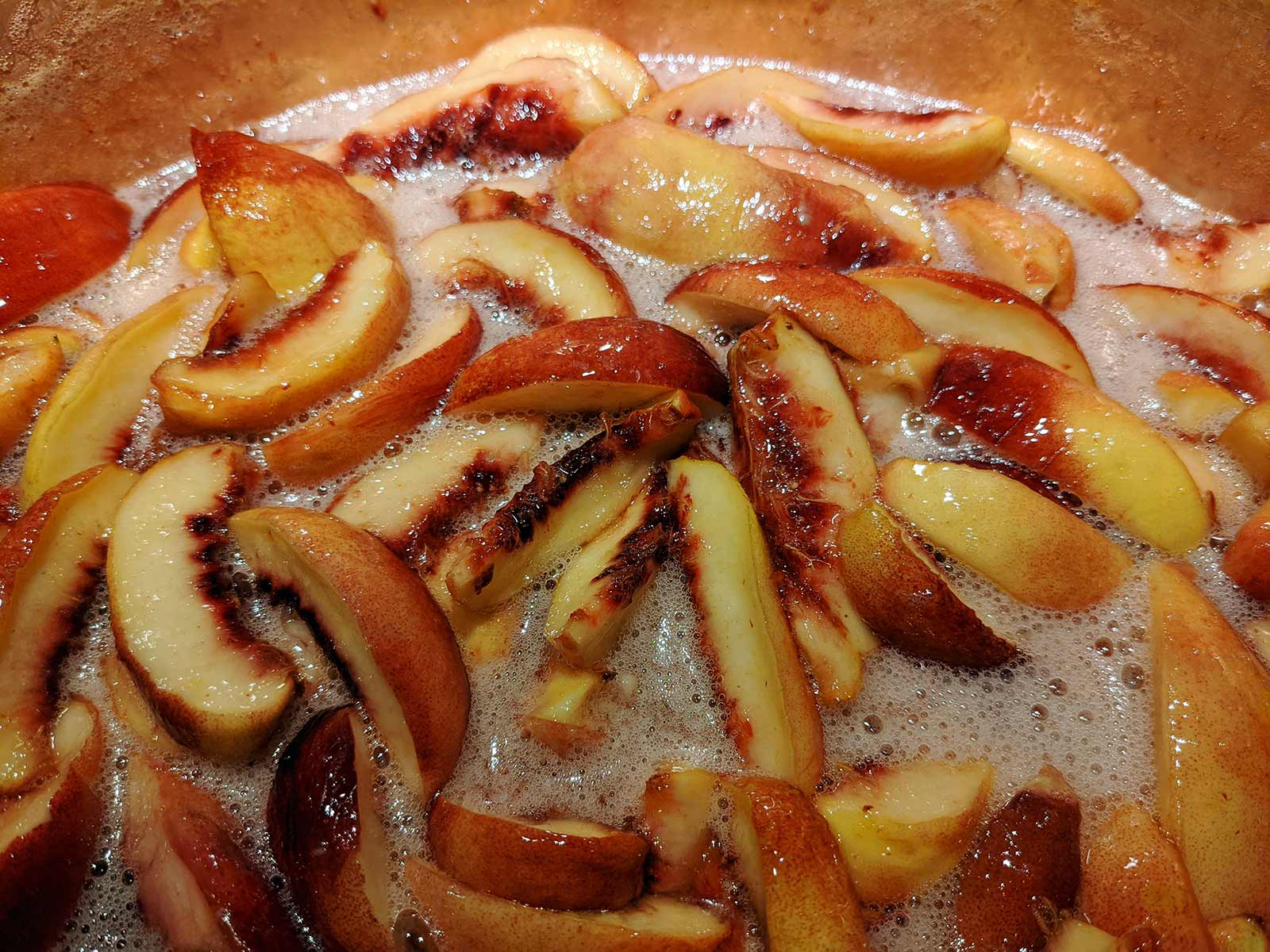 White nectatines cooking in copper pan